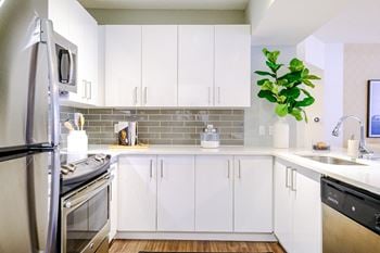 Well-appointed kitchen with quartz countertops & glass backsplash